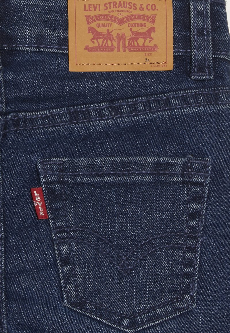 Dunkelblaue Jeans aus Denim mit einer rechteckigen Gesäßtasche, versehen mit einem roten Levi's-Label und einer gestickten Design über der Tasche. Lederetiquette mit Branding.