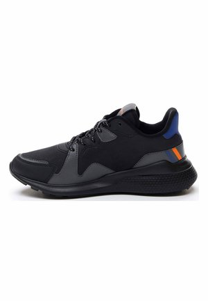 Black athletic shoe featuring a textured rubber sole, mesh upper, grey overlays, and blue and orange accents on the heel.