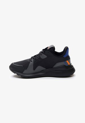 Black athletic shoe featuring a textured rubber sole, mesh upper, grey overlays, and blue and orange accents on the heel.