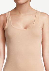 Canotta in cotone beige con ampie spalline e scollo tondo, caratterizzata da una texture liscia ed elastica e una silhouette aderente.