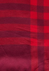 Tela de cuadros roja y rojo oscuro con una textura suave; presenta rayas verticales y horizontales de diferentes anchos.