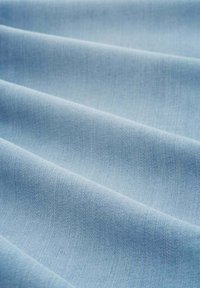 Helles blaues Gewebe mit glatter Textur, das subtile diagonale Linien und ein gewebtes Muster aufweist, wodurch es weich und fließend aussieht.