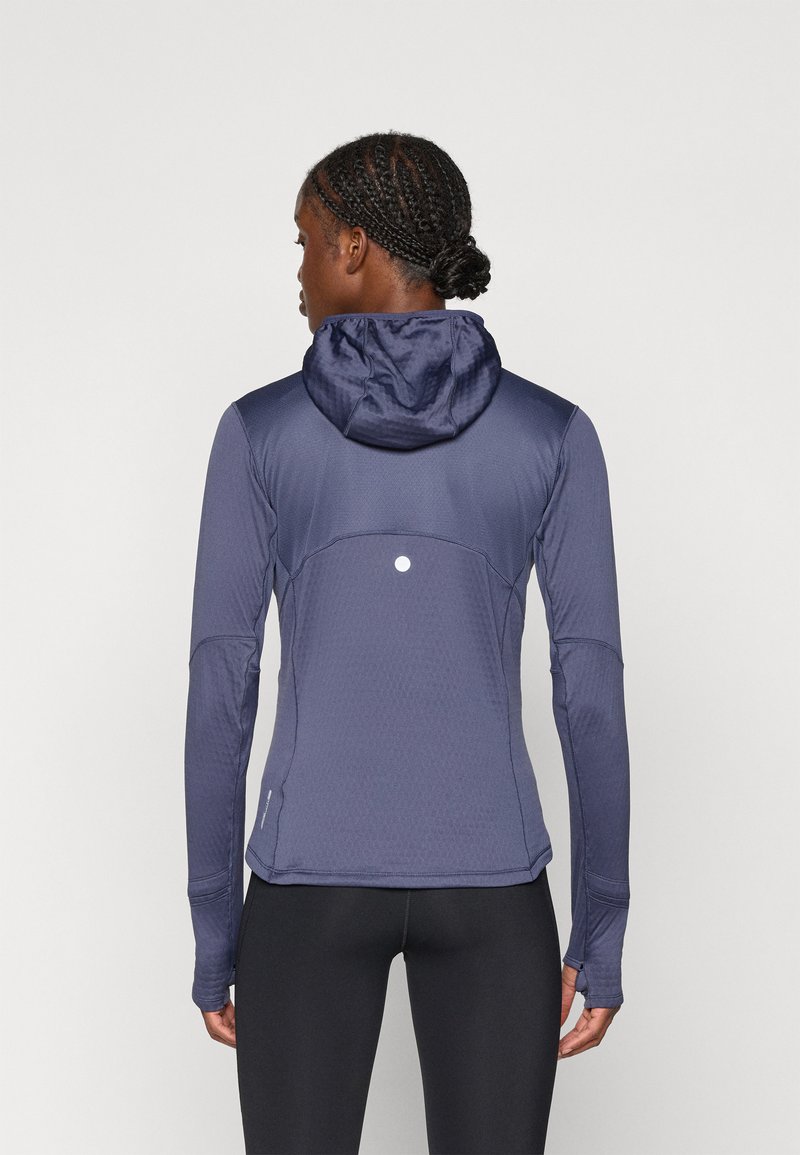 Navy blue long-sleeve athletic jacket with a hood, featuring textured fabric, a subtle logo on the back, and fitted design.