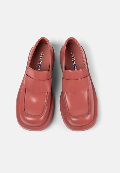 Red leather shoes with a rounded toe, a wide strap across the upper, and a thick sole featuring a smooth, glossy finish.