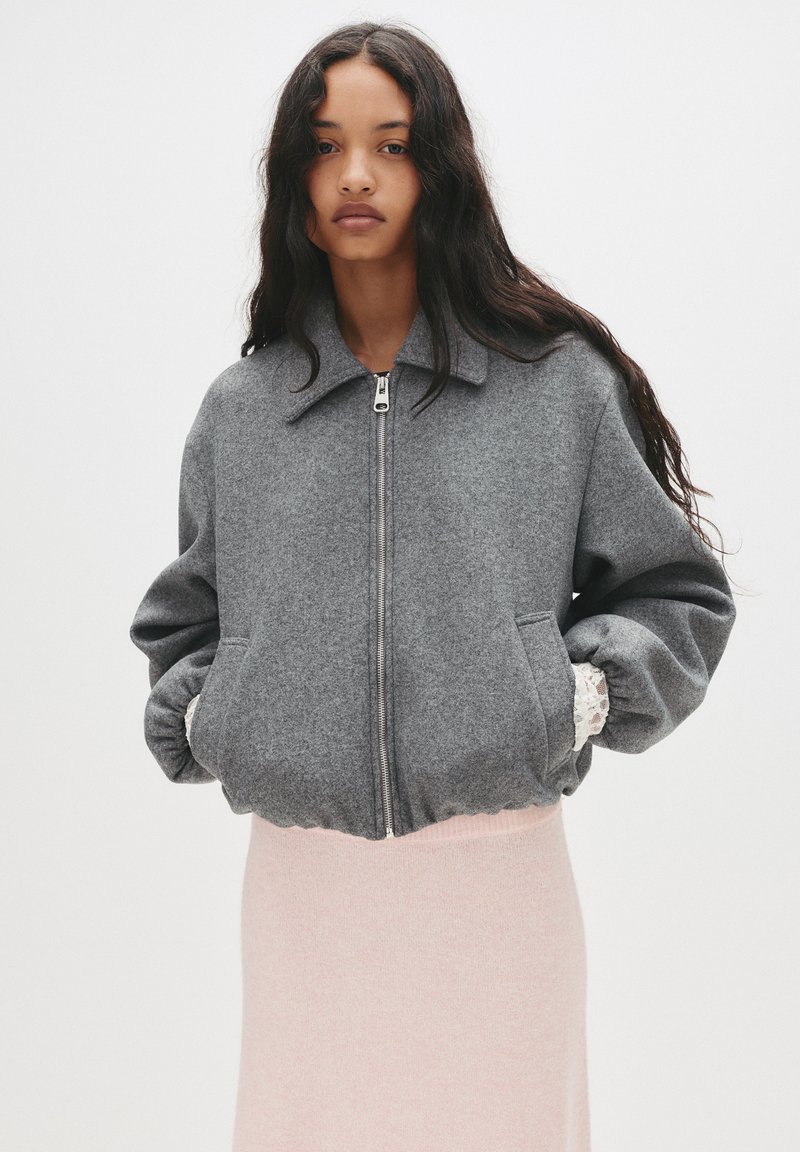 Graue Wollmischung Bomberjacke mit Reißverschluss, Kragen und elastischen Bündchen, mit Seitentaschen und texturierter Oberfläche.