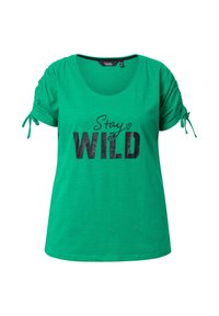 Groene T-shirt met een ronde hals, korte puffmouwen met strikjes, en een zwarte grafische print met de tekst "Stay WILD."