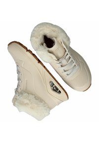 Beige Sneakers mit Kunstfellfutter und strukturiertem Obermaterial, Schnürdesign und einem transparenten Luftpolster in der Sohle. Gummiaußensohle für besseren Halt.