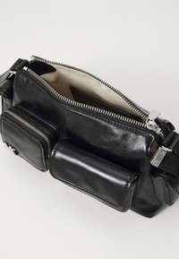 Bolso estilo bandolera de piel negra con herrajes plateados, compartimento principal con cremallera, dos bolsillos exteriores y una textura suave y brillante.