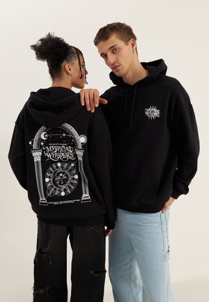 Black hoodies feature graphic designs on the back and front. One has a celestial theme with text, while the other has a smaller logo on the chest.