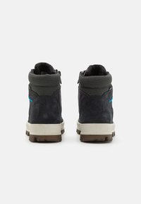 Botines de ante negros con cuellos de punto gris, que presentan un acento azul. Suelas de goma ligeras, con textura antideslizante para mayor tracción.