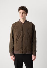 Brown, padded bomber jacket with a ribbed collar and cuffs. Features a front zipper and two side pockets, made from a smooth material.