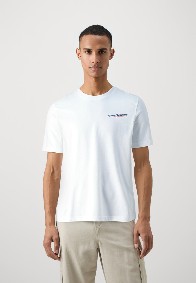 T-shirt bianco a maniche corte in cotone con scollatura rotonda, caratterizzato da un logo colorato "Diesel Industry" sul lato sinistro del petto.