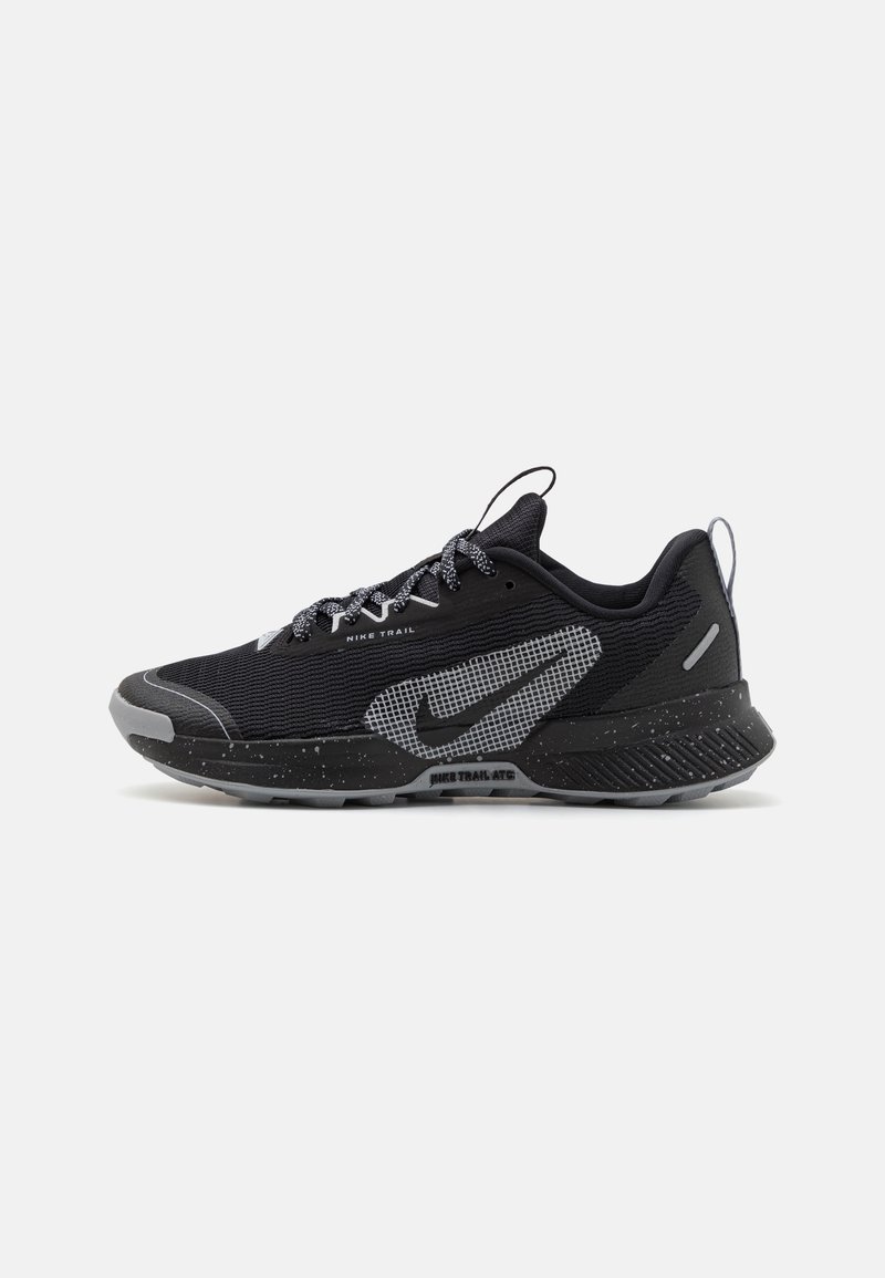 Chaussure de trail Nike noire et grise avec tige en mesh, semelle intermédiaire tachetée, fermeture à lacets et languettes de traction sur la languette et le talon.