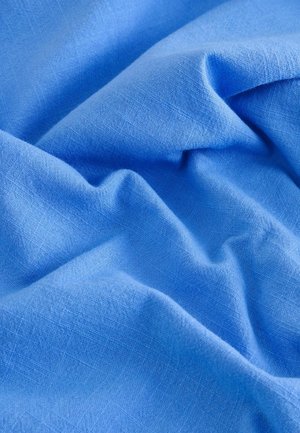 Jasnoniebieska tkanina o gładkiej fakturze, ukazująca miękkie fałdy i subtelny wzór splotu. Idealna do odzieży lub tekstyliów domowych.