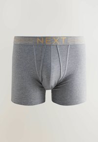Szürke pamut boxer alsónadrág arany csíkkal díszített rugalmas derékkal, amelyen a "NEXT" felirat olvasható. Simára kidolgozott textúra, közepes hosszúságú dizájn, szegélyezett részletekkel.