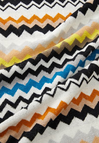 Colorful zigzag patterned fabric featuring black, orange, blue, yellow, white, and gray tones. Soft texture with towel-like material.