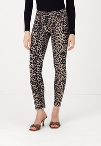 Pantaloni skinny con stampa leopardata, con una base beige e macchie nere, dotati di design classico a cinque tasche e orli sfilacciati.