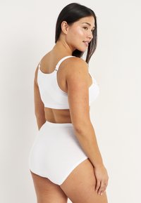 Soutien-gorge blanc et culotte taille haute en tissu lisse, dotés de bretelles réglables. Design sans coutures avec des bords subtils et sans motifs.
