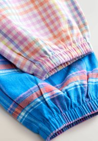 Plaid medžiaga pastelinių spalvų su elastinga rankove. Viršutinė dalis yra švelnių atspalvių su rožiniais ir oranžiniais languotais raštais, apatinė dalis - ryškiai mėlyna.