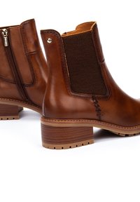 Braune Leder-Stiefeletten mit elastischen Seiteneinsätzen, einem Blockabsatz und dekorativen Nähten. Verfügt über einen Reißverschluss für ein bequemes An- und Ausziehen.