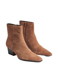Bottines en daim marron avec un bout pointu, un talon bas et une fermeture éclair sur le côté. Texture lisse et design ajusté au niveau de la cheville.