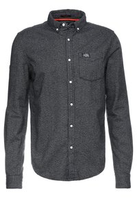 Camisa gris abotonada hecha de tela texturizada, con cuello, mangas largas, un bolsillo en el pecho y un pequeño parche con logotipo.