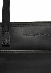 Borsa a mano in pelle nera con texture liscia, dettagli cuciti e marchio in rilievo "The Chesterfield Brand". Manici integrati nel design.
