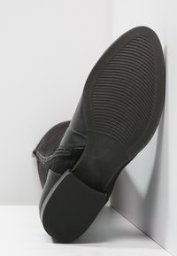 Stivale alla caviglia nero con chiusura a zip e parte superiore testurizzata. Presenta una suola piatta in gomma con scanalature orizzontali per una migliore trazione.