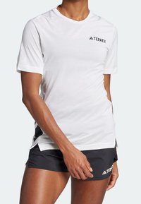 Camiseta blanca de manga corta con el logo negro de TERREX, hecha de tejido ligero; paneles de malla en los laterales para transpirabilidad y comodidad.