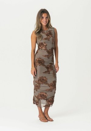 Knielanges Kleid aus beigem Stoff mit brauner floralem Stickerei, mit figurbetontem Design und Kurzärmeln. Kombiniert mit flachen Sandalen.