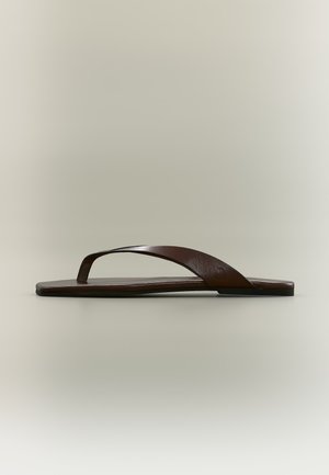 Sandale plate marron type tongs avec un design simple de sangle et une texture lisse, vue de profil sur un fond neutre.