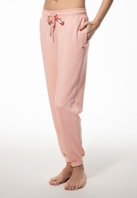 Roze, lichte joggingbroek met een elastische tailleband, verstelbaar trekkoord, zijzakken en boorden bij de enkels, gemaakt van zachte stof.
