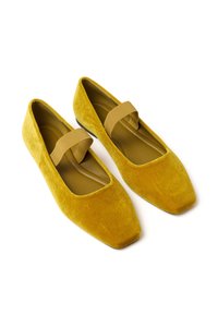 Gelbe Samt-Ballettschuhe verfügen über eine quadratische Zehenform und ein weiches elastisches Band über dem Spann. Die glatte Textur verstärkt ihre visuelle Anziehungskraft.