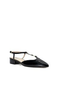 Chaussure slingback en vernis noir avec un bout pointu, un design en T-strap et un petit talon bloc. Accentuée d'un détail de boucle en or.