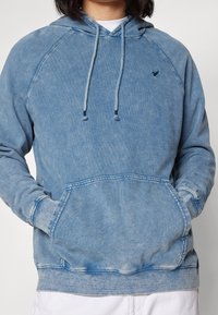 Ljusa blå, bomulls hoodie med känguruficka, justerbara dragsko och raglanärmar. Blekt mönster med en liten logotypdetalj.