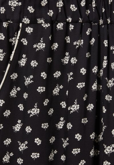 Tela negra con pequeños patrones florales en blanco, con plisados y una cinturilla elástica. Textura suave adecuada para uso casual o formal.