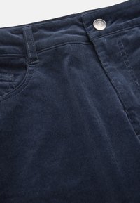 Dark blue corduroy fabric with a soft texture, featuring a metal button at the waist and a classic five-pocket design.