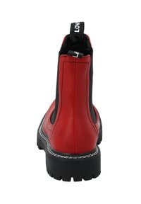 Botín de tobillo rojo de cuero con laterales elásticos negros, costuras blancas y una pestaña para tirar. Suela resistente de goma negra con un patrón texturizado.