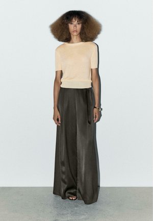 Krótki rękaw brzoskwiniowy sweter z dzianiny w połączeniu z ciemnoszarymi, szerokimi satynowymi spodniami. Miękka tekstura, luźny krój i gładkie wykończenie.