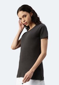 Maglietta nera a maniche corte con colletto rotondo, realizzata in cotone morbido. Design aderente con dettagli di cucitura laterale discreti.