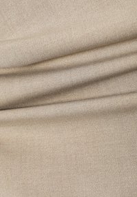 Beige kangas, joka on sileä ja jossa on himmeä kudontakuosi, sisältää pehmeitä poimuja ja tasaisen mattapinnan.