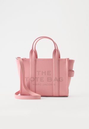 Petit sac cabas en cuir rose avec deux anses et une longue bandoulière, avec "The Tote Bag Marc Jacobs" embossé à l'avant.