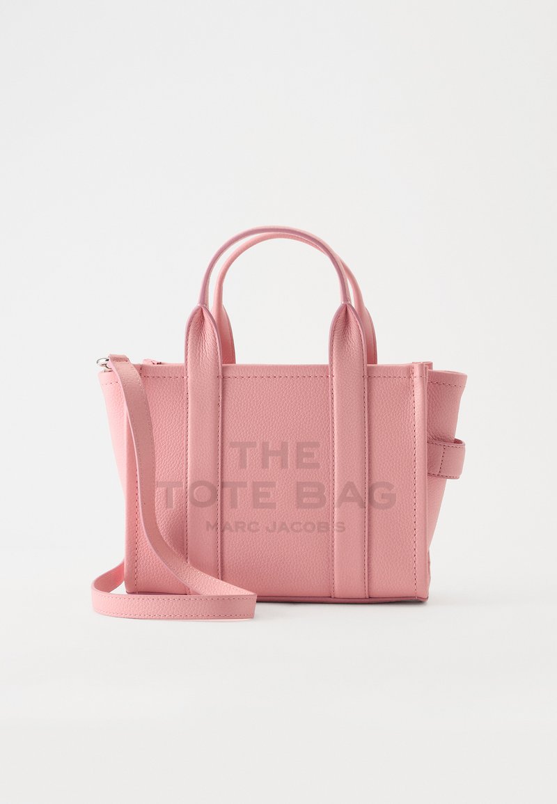 Petit sac cabas en cuir rose avec deux anses et une longue bandoulière, avec "The Tote Bag Marc Jacobs" embossé à l'avant.