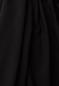 Tissu noir avec une texture lisse et tissée, présentant des plis doux et des plis irréguliers. Aucun motif ni détail de matériel visible.