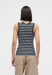 Μπλε ναυτικό και λευκό ριγέ τοπ χωρίς μανίκια με εφαρμοστή σχεδίαση, διαθέτει φαρδιές τιράντες στους ώμους και στρογγυλή λαιμόκοψη, συνδυασμένο με καφέ, άνετο παντελόνι.