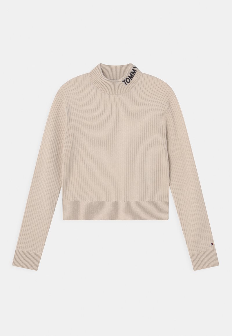 Pull en maille côtelée beige à manches longues avec col montant, texte "TOMMY" sur le col et petit logo drapeau sur le poignet gauche.