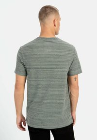 Gråstribet kortærmet t-shirt med rund halsudskæring, der har en subtil tekstur og en løs pasform, parret med sorte bukser.