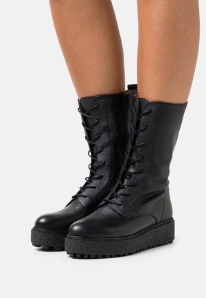 Mustat nahkaiset nauhalliset saappaat, joissa on teksturoitu pinta, korkea varsi ja paksu musta korokepohja, jossa on karkea kuviointi.