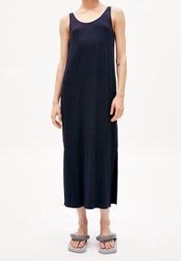 Marinblå ärmlös maxikjol tillverkad av mjukt tyg, med rund halsringning och sprund i sidorna. Matchas med grå klumpiga sandaler.