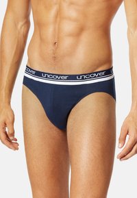 Dunkelblaue Unterwäsche aus weichem Material mit einem elastischen Bund in Weiß und Blau, der mit "uncover"-Branding versehen ist. Glatte Textur und eng anliegende Passform.